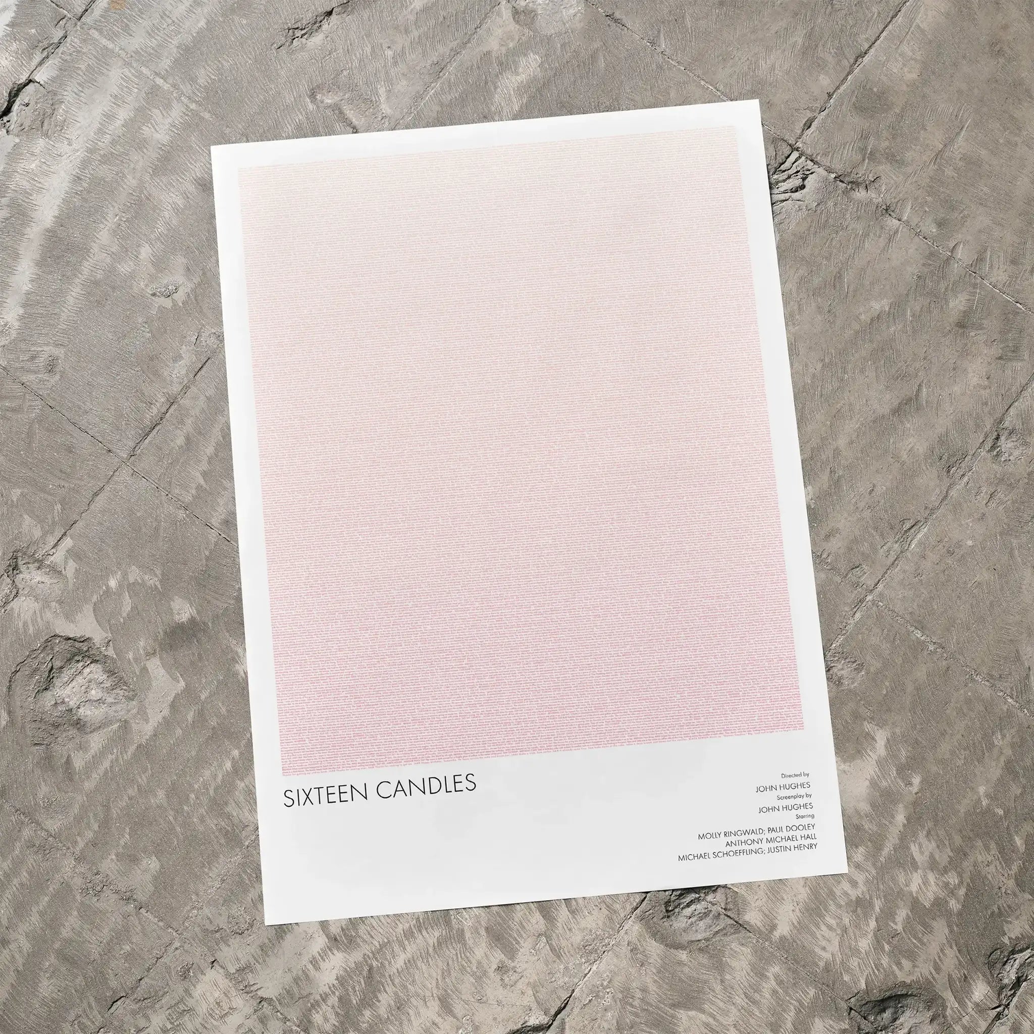 A Sixteen Candles movie script poster laid flat on a textured floor surface.