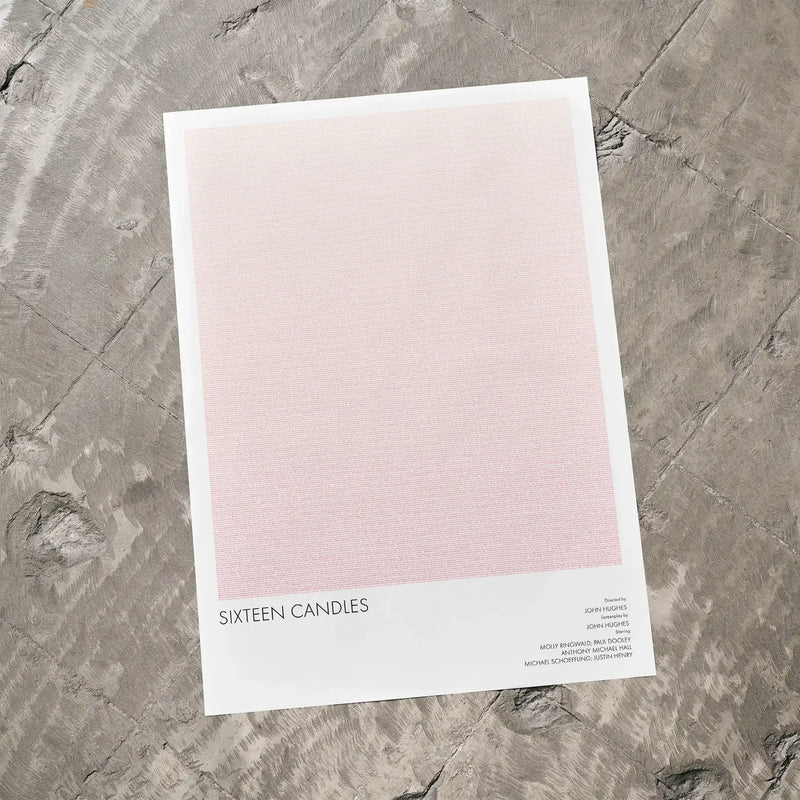 A Sixteen Candles movie script poster laid flat on a textured floor surface.
