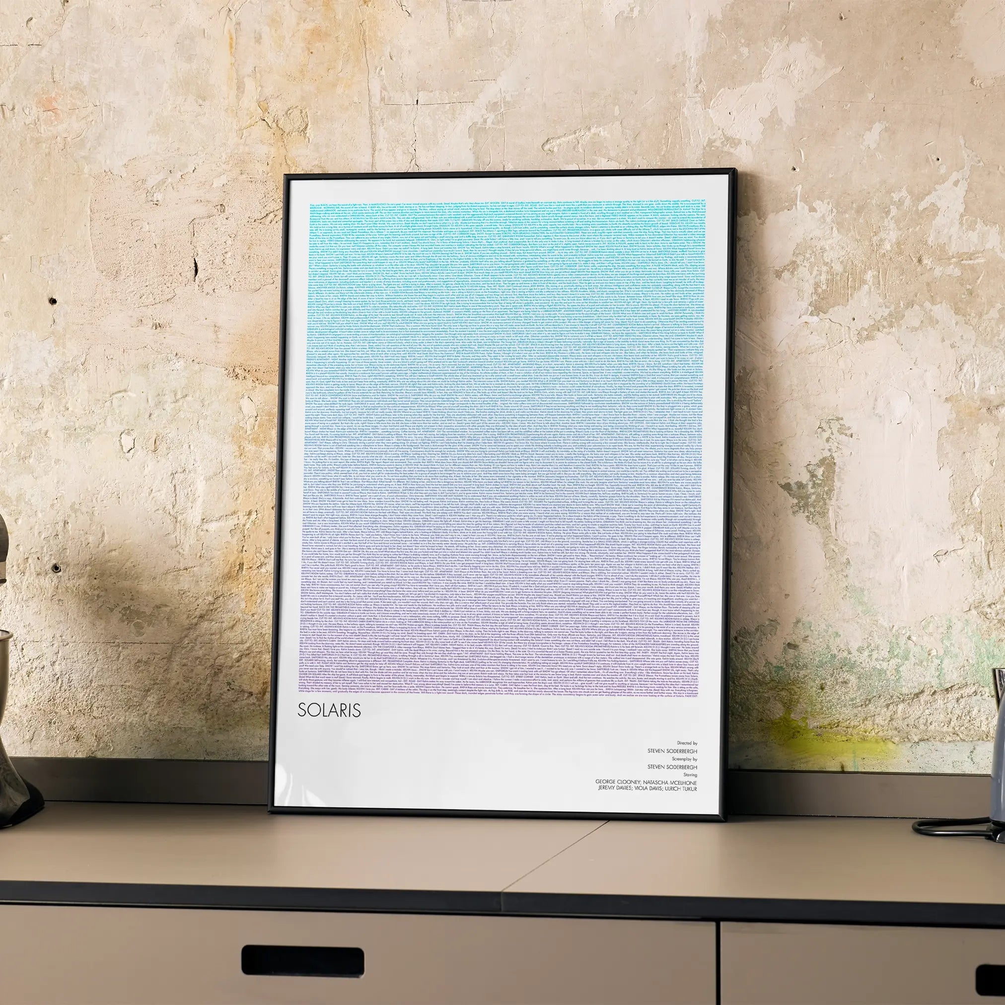 A framed Solaris movie script poster displayed on a cabinet in a minimalist interior.