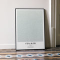 A framed Stalker movie script poster leaning against a wall in a minimalist interior.