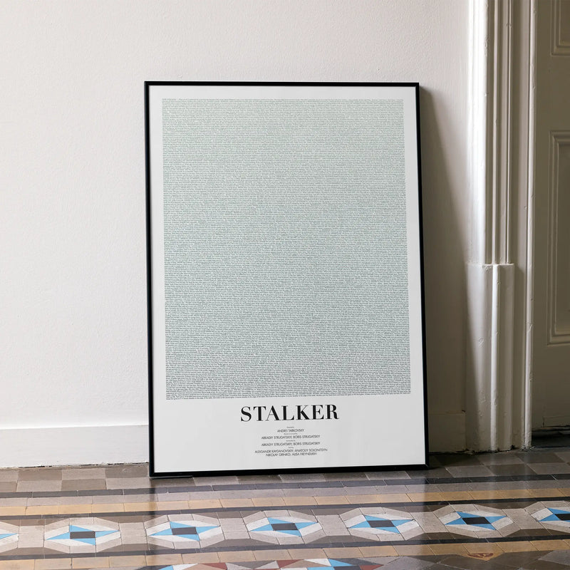 A framed Stalker movie script poster leaning against a wall in a minimalist interior.