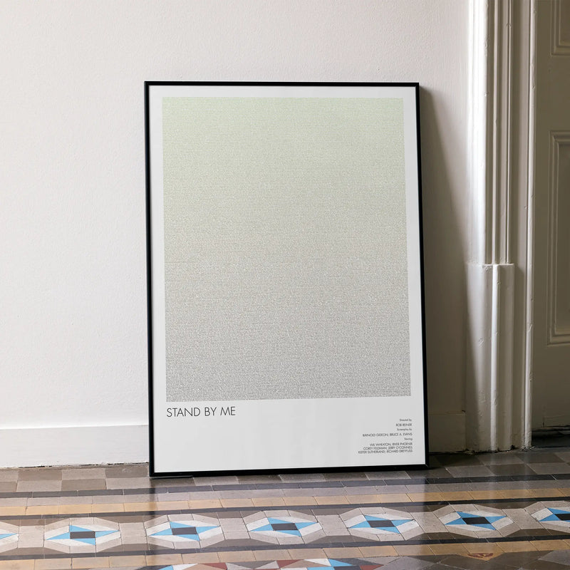 A framed Stand by Me movie script poster leaning against a wall in a minimalist interior.