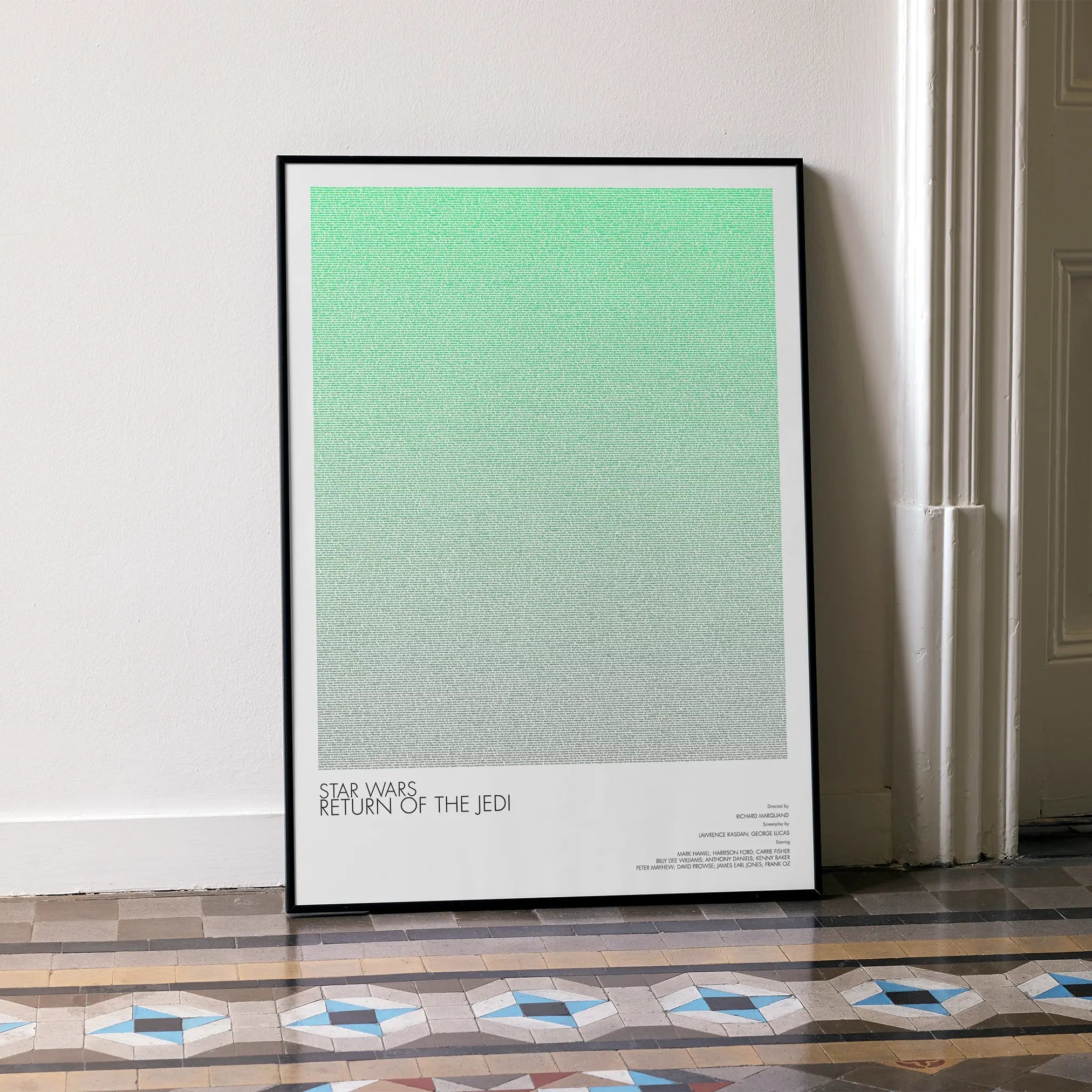 A framed Star Wars: Return of the Jedi movie script poster leaning against a wall in a minimalist interior.