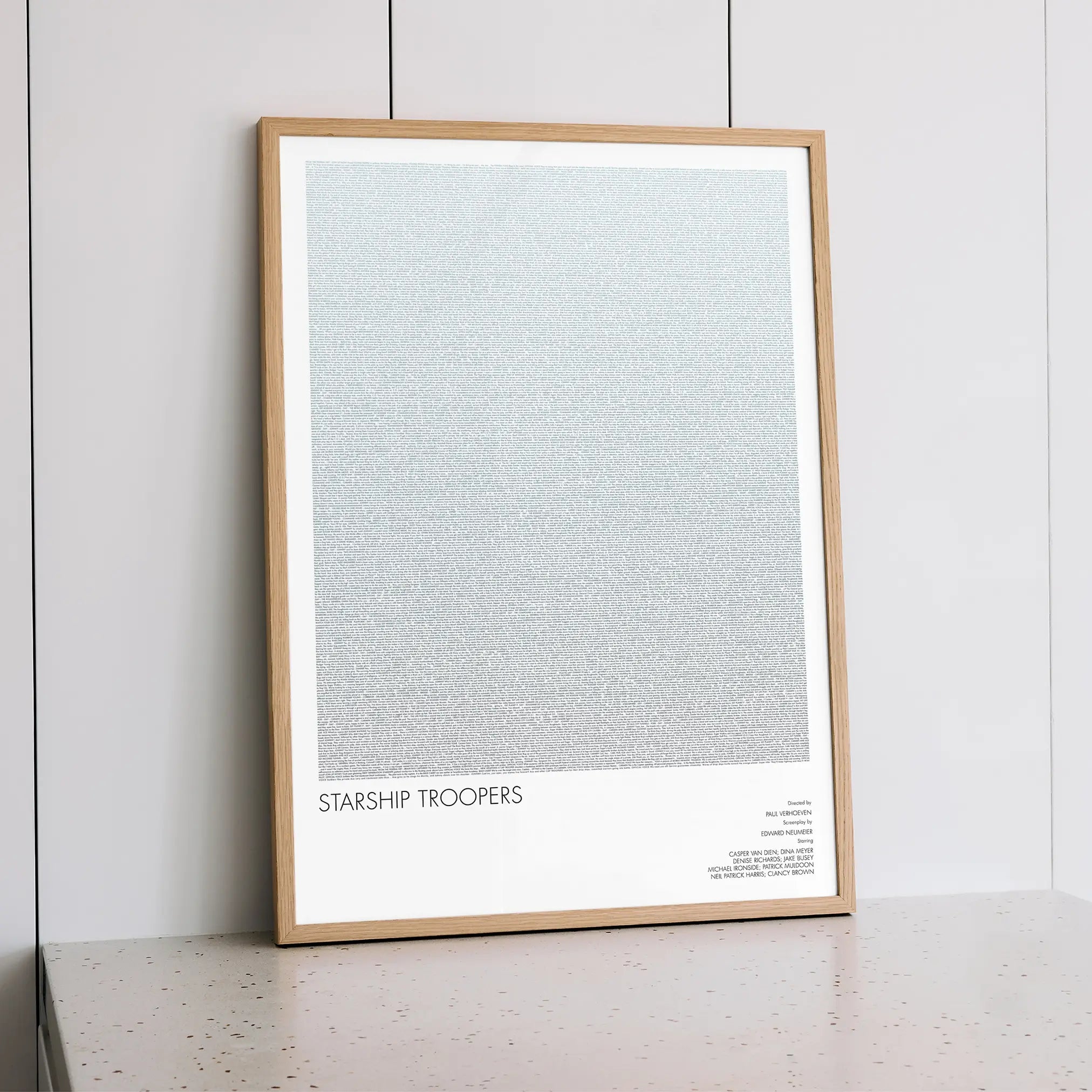A framed Starship Troopers movie script poster styled within a calm interior space.