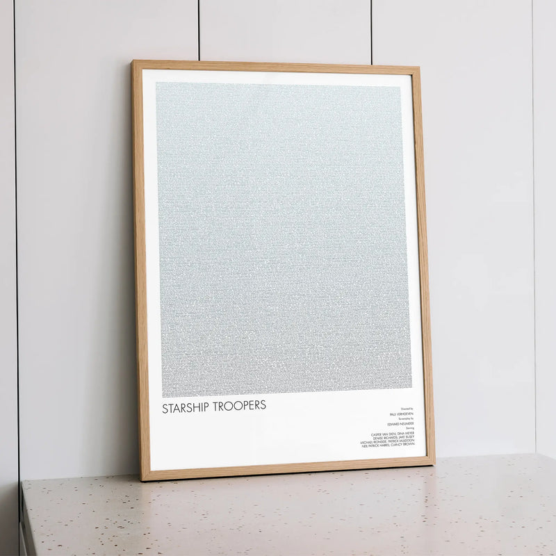 A framed Starship Troopers movie script poster styled within a calm interior space.