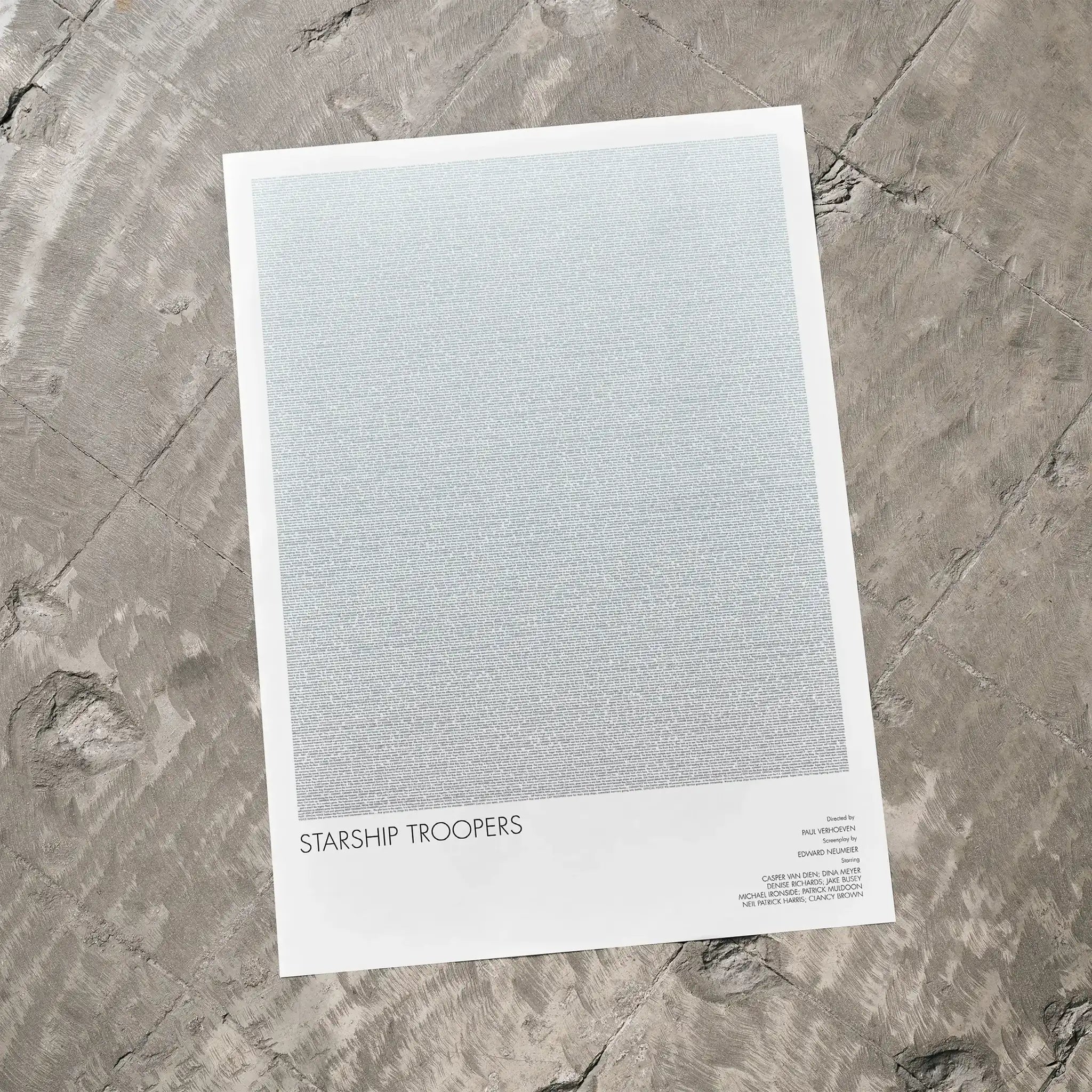A Starship Troopers movie script poster laid flat on a textured floor surface.