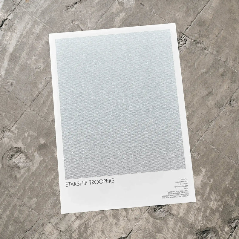 A Starship Troopers movie script poster laid flat on a textured floor surface.