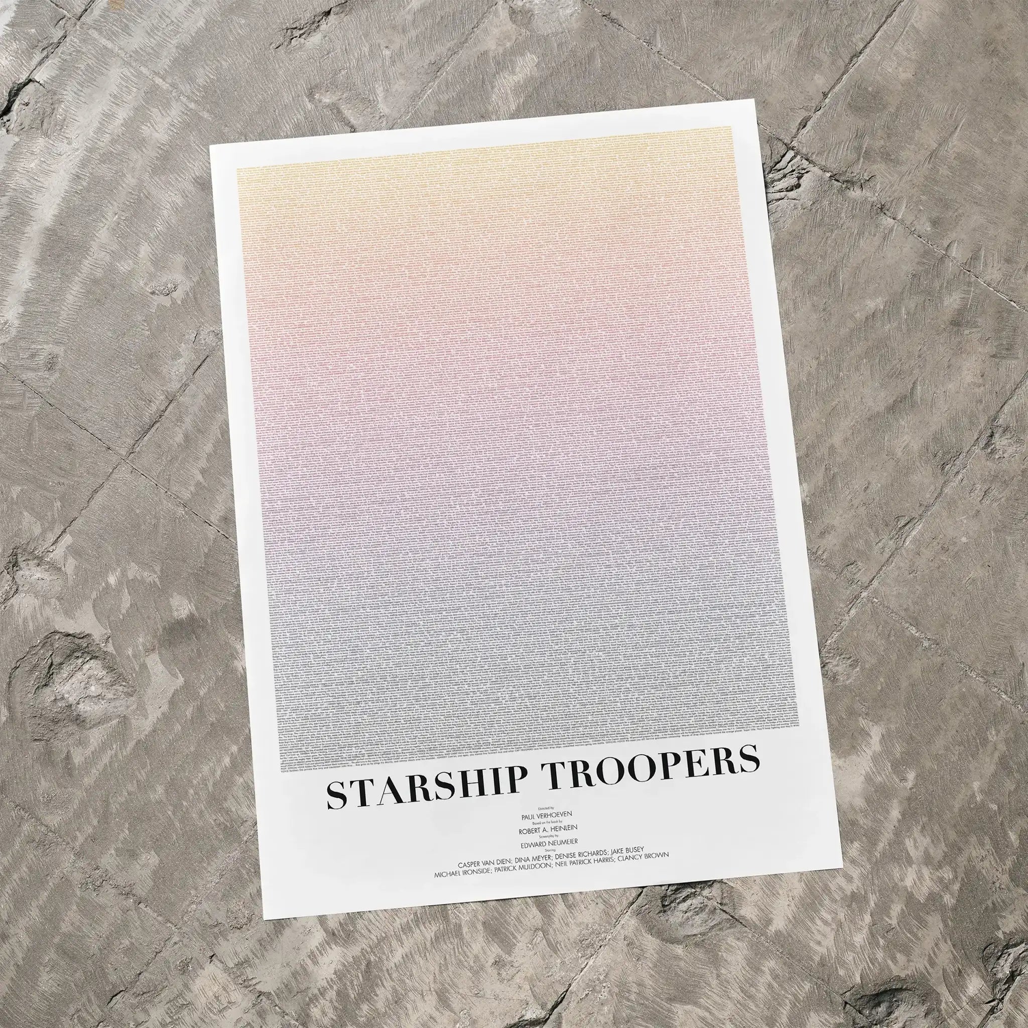 A Starship Troopers movie script poster laid flat on a textured floor surface.
