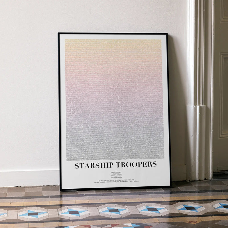 A framed Starship Troopers movie script poster leaning against a wall in a minimalist interior.