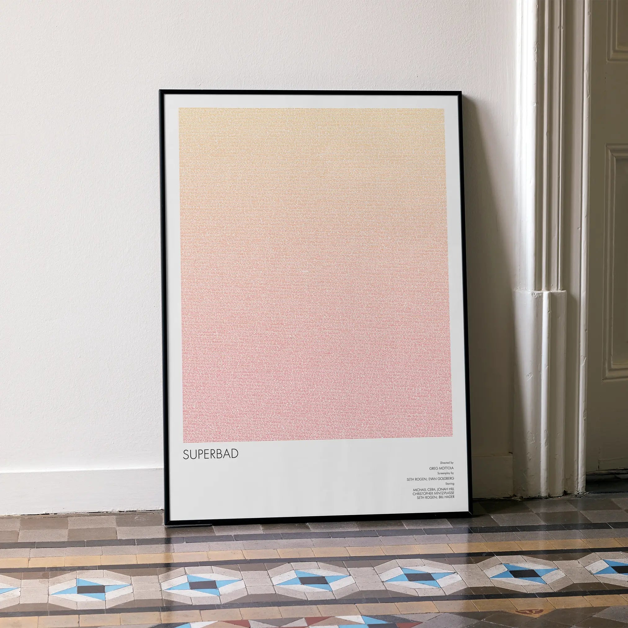 A framed Superbad movie script poster leaning against a wall in a minimalist interior.