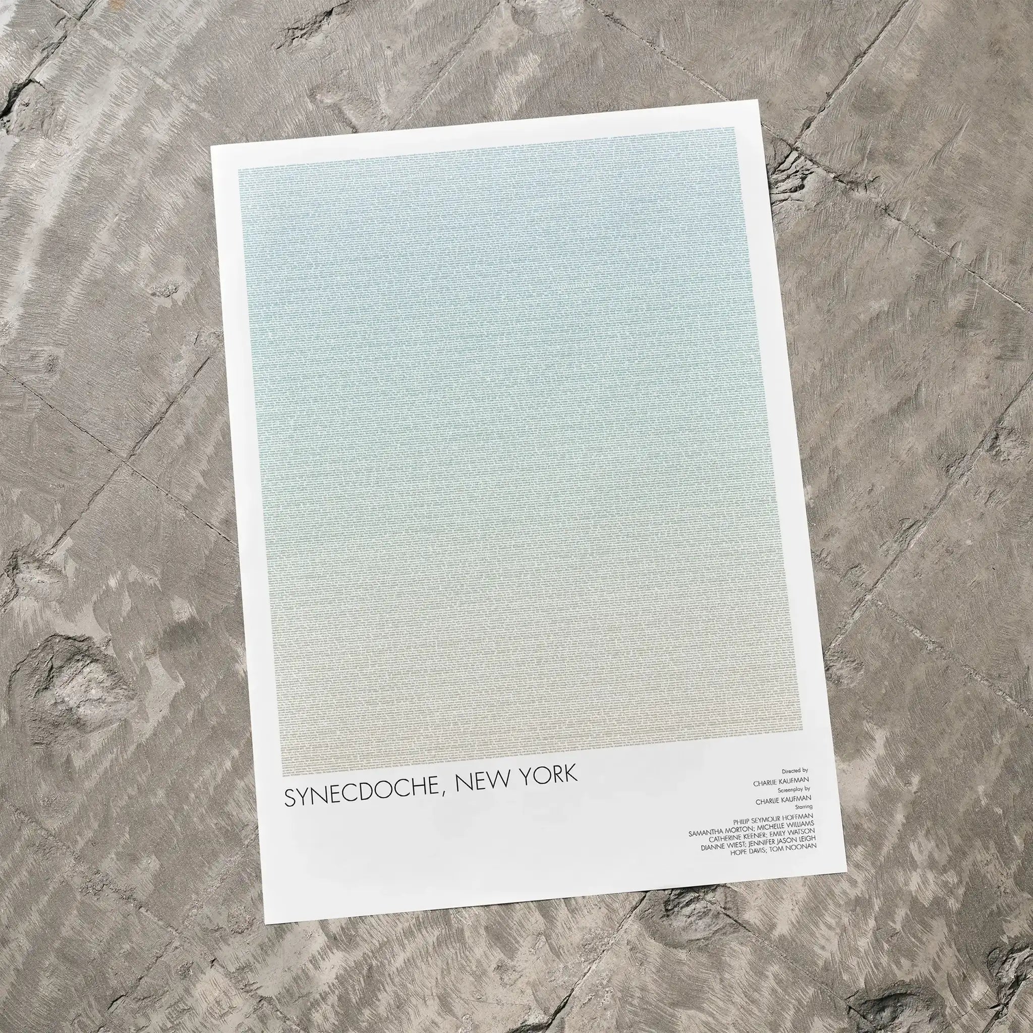 A Synecdoche, New York movie script poster laid flat on a textured floor surface.