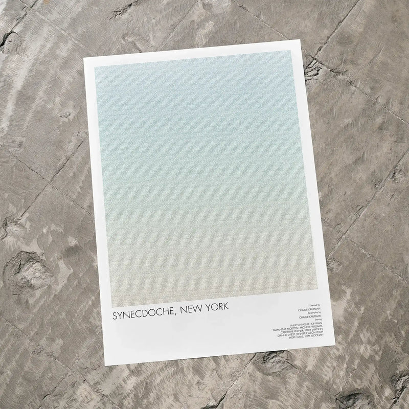 A Synecdoche, New York movie script poster laid flat on a textured floor surface.