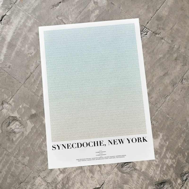 A Synecdoche, New York movie script poster laid flat on a textured floor surface.