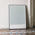 A framed Tár movie script poster leaning against a wall in a minimalist interior.