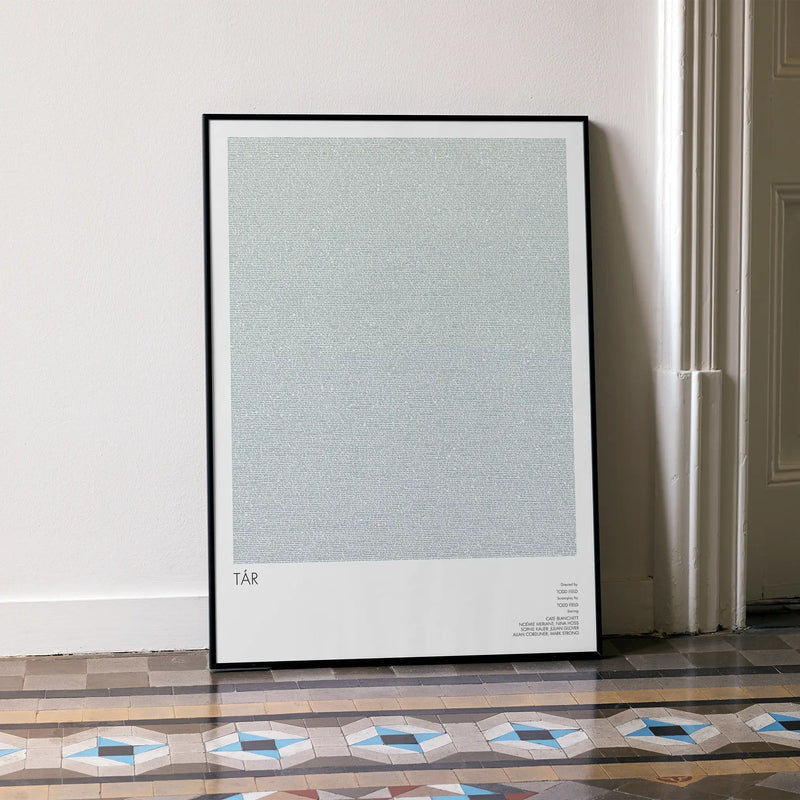 A framed Tár movie script poster leaning against a wall in a minimalist interior.