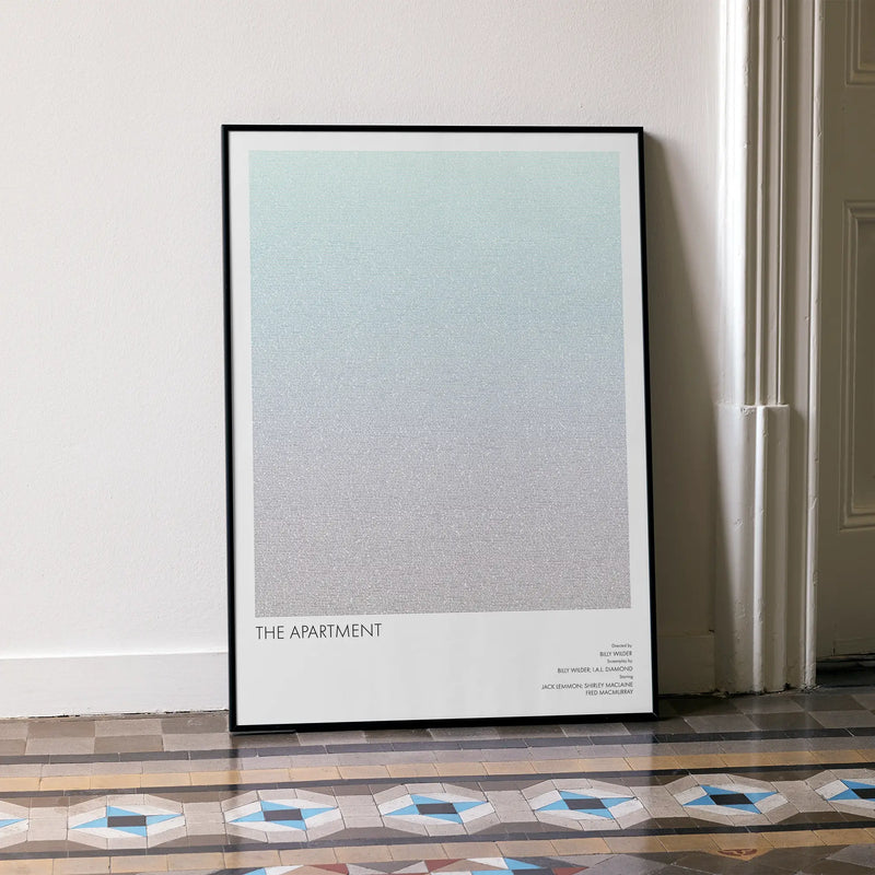 A framed The Apartment movie script poster leaning against a wall in a minimalist interior.