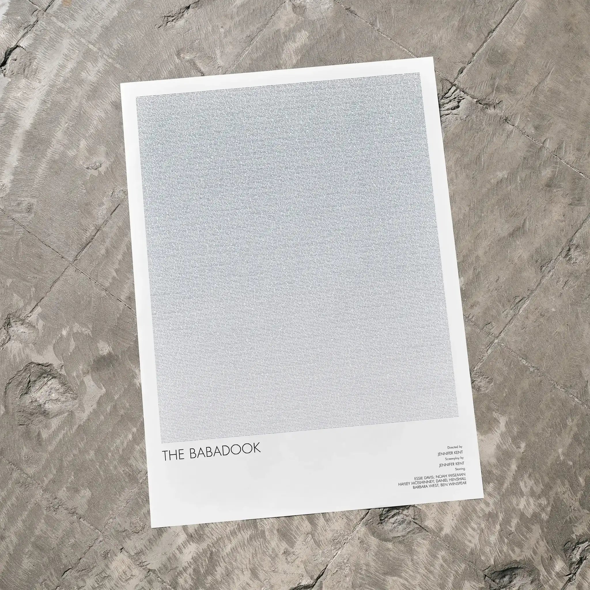 A The Babadook movie script poster laid flat on a textured floor surface.