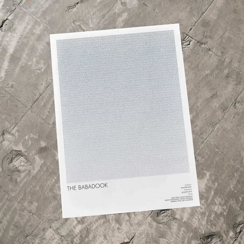 A The Babadook movie script poster laid flat on a textured floor surface.
