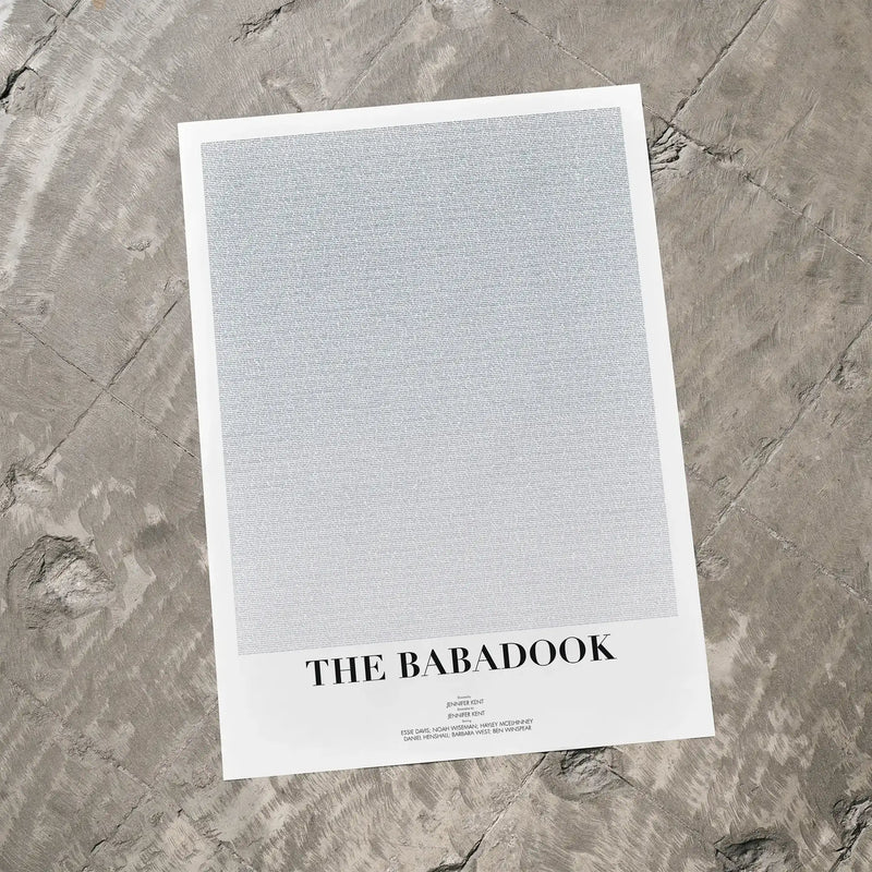 A The Babadook movie script poster laid flat on a textured floor surface.