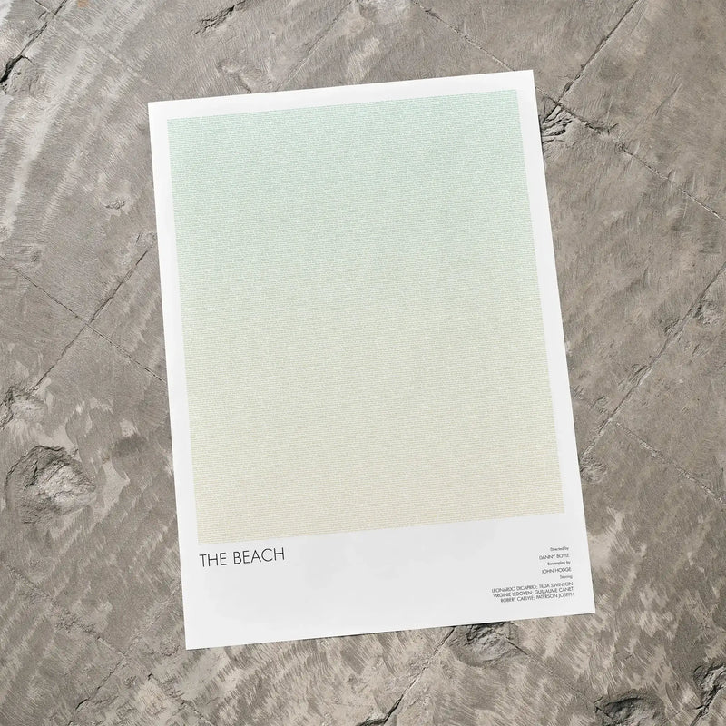 A The Beach movie script poster laid flat on a textured floor surface.