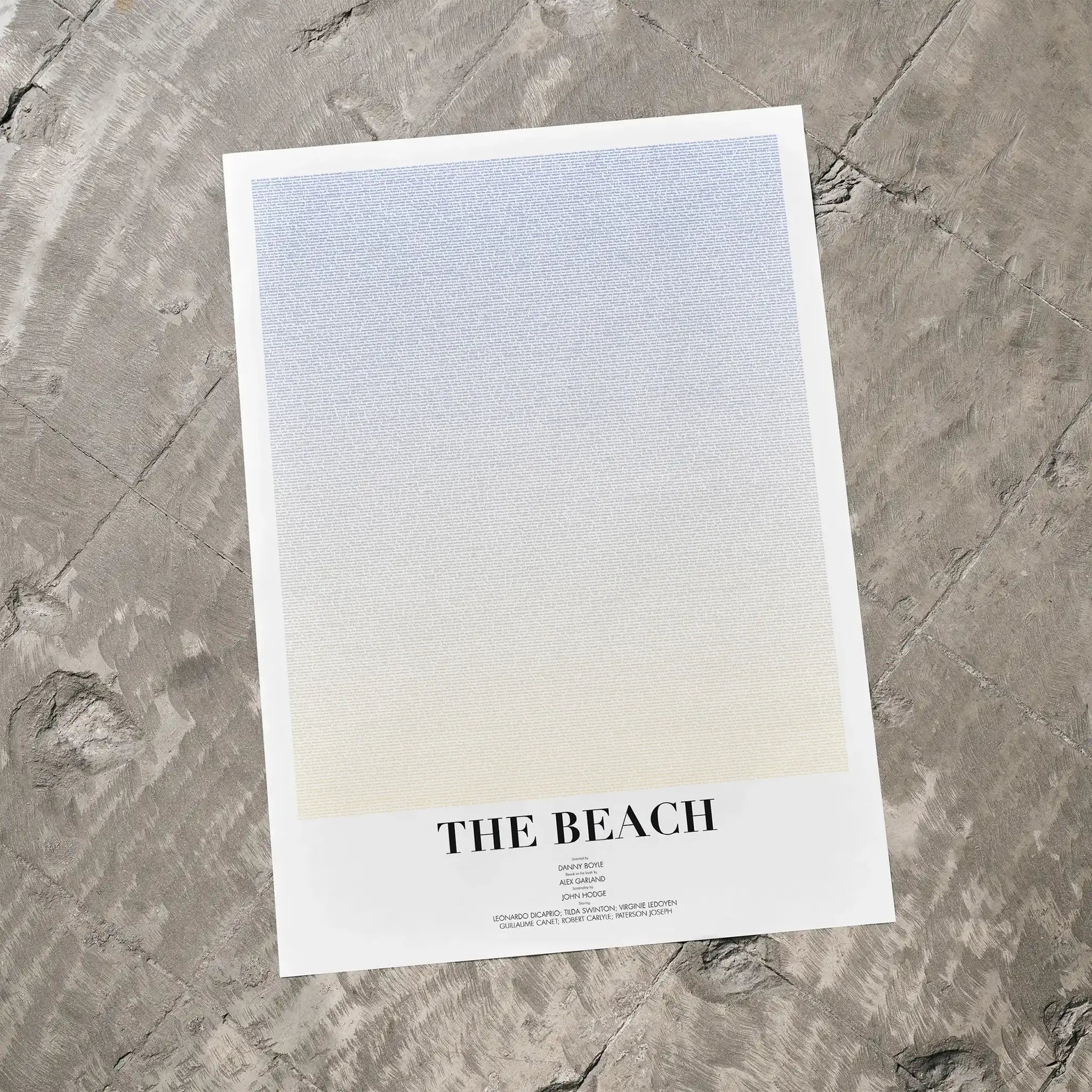 A The Beach movie script poster laid flat on a textured floor surface.