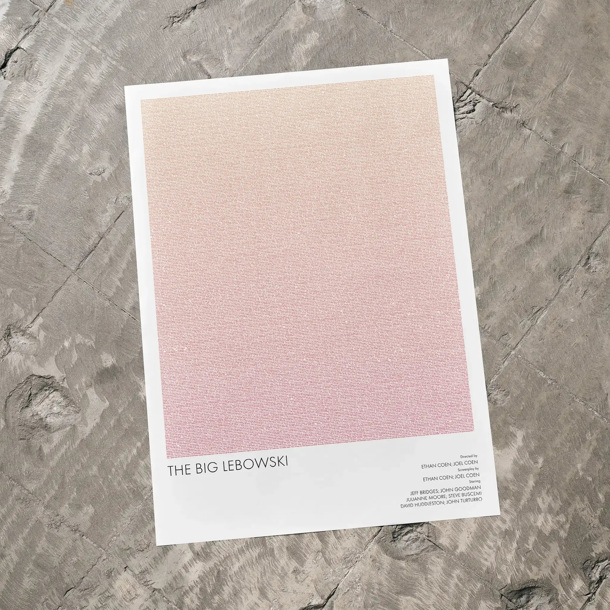 A The Big Lebowski movie script poster laid flat on a textured floor surface.