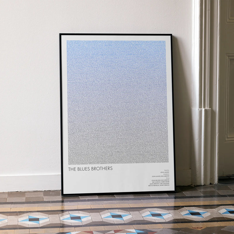 A framed The Blues Brothers movie script poster leaning against a wall in a minimalist interior.