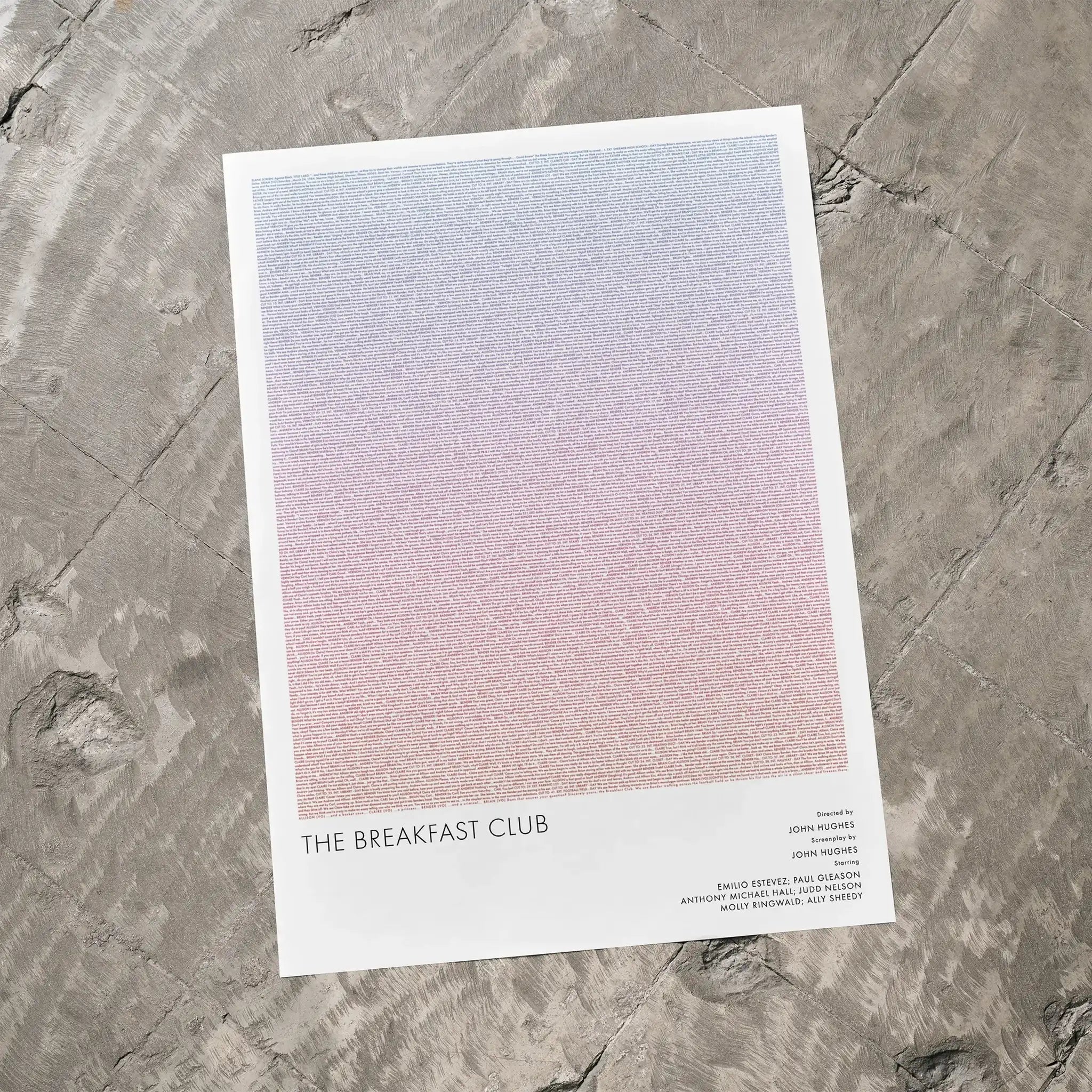 A The Breakfast Club movie script poster laid flat on a textured floor surface.