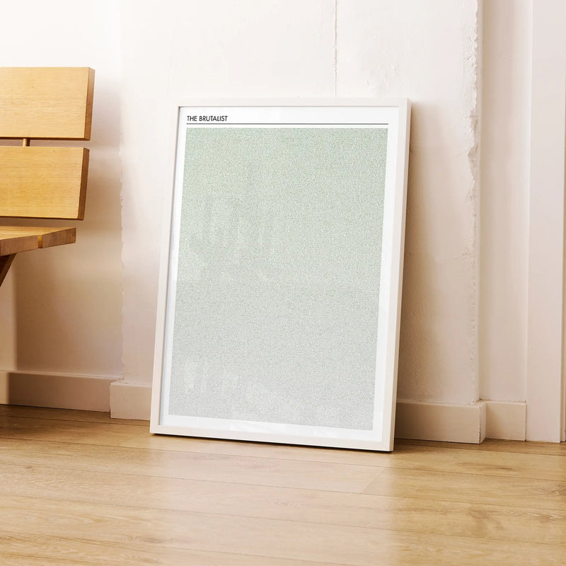 A framed The Brutalist movie script poster leaning against a wall in a modern interior.