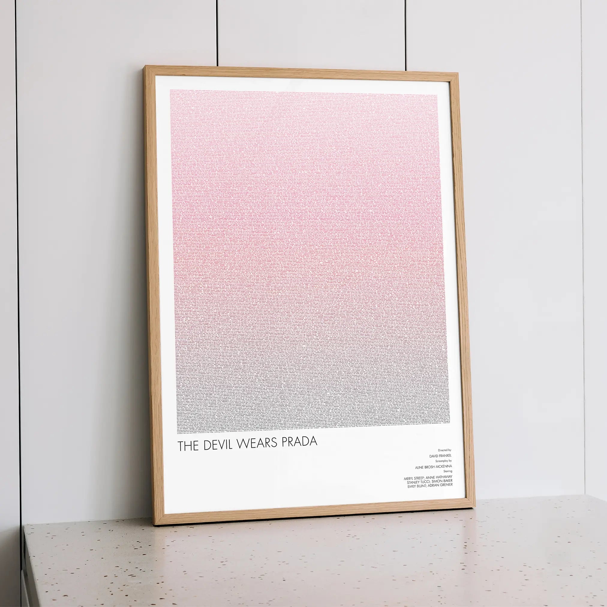A framed The Devil Wears Prada movie script poster styled within a calm interior space.