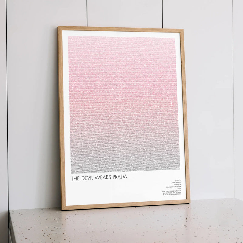 A framed The Devil Wears Prada movie script poster styled within a calm interior space.