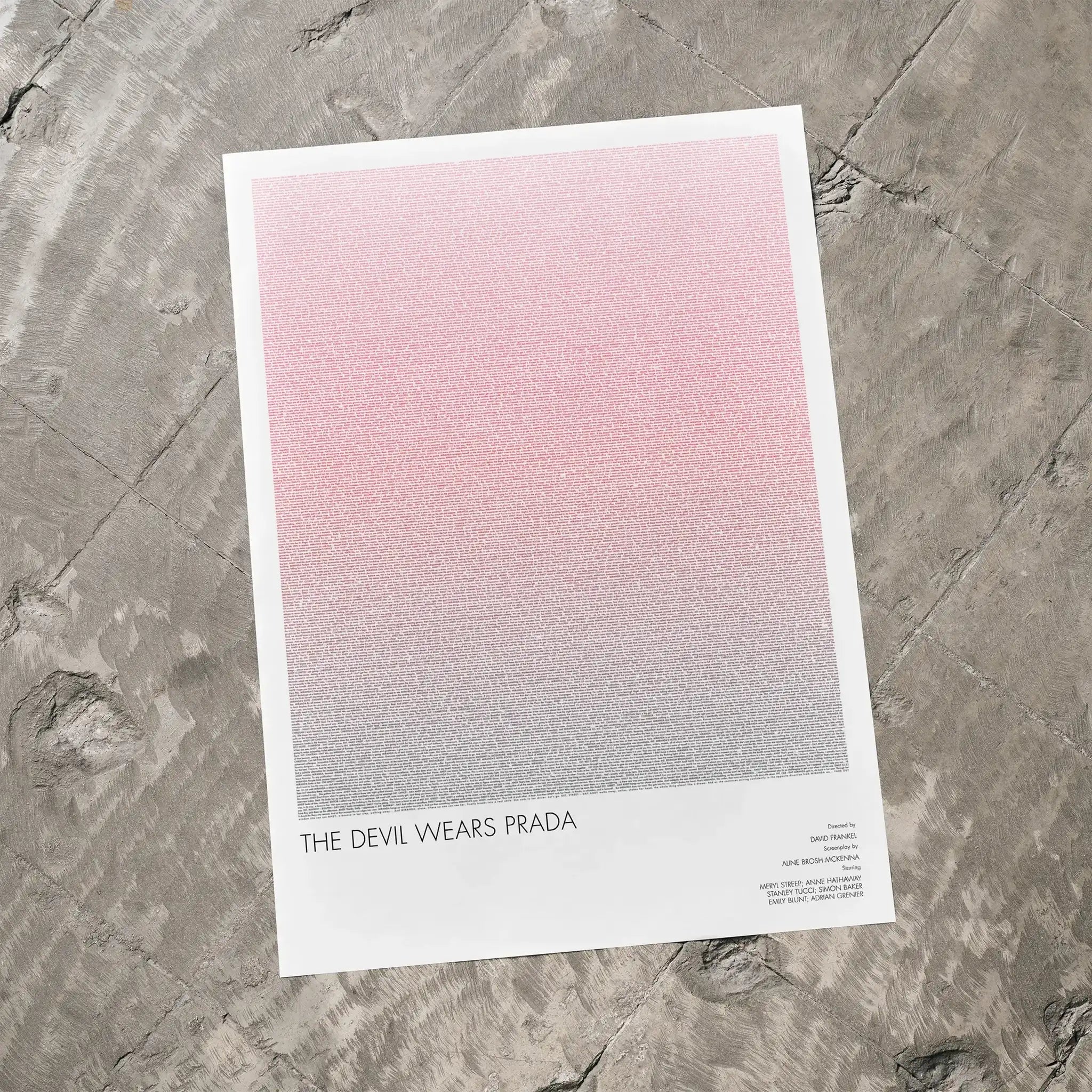 A The Devil Wears Prada movie script poster laid flat on a textured floor surface.