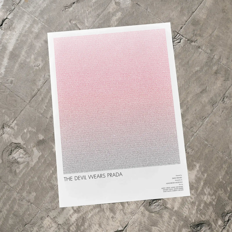 A The Devil Wears Prada movie script poster laid flat on a textured floor surface.