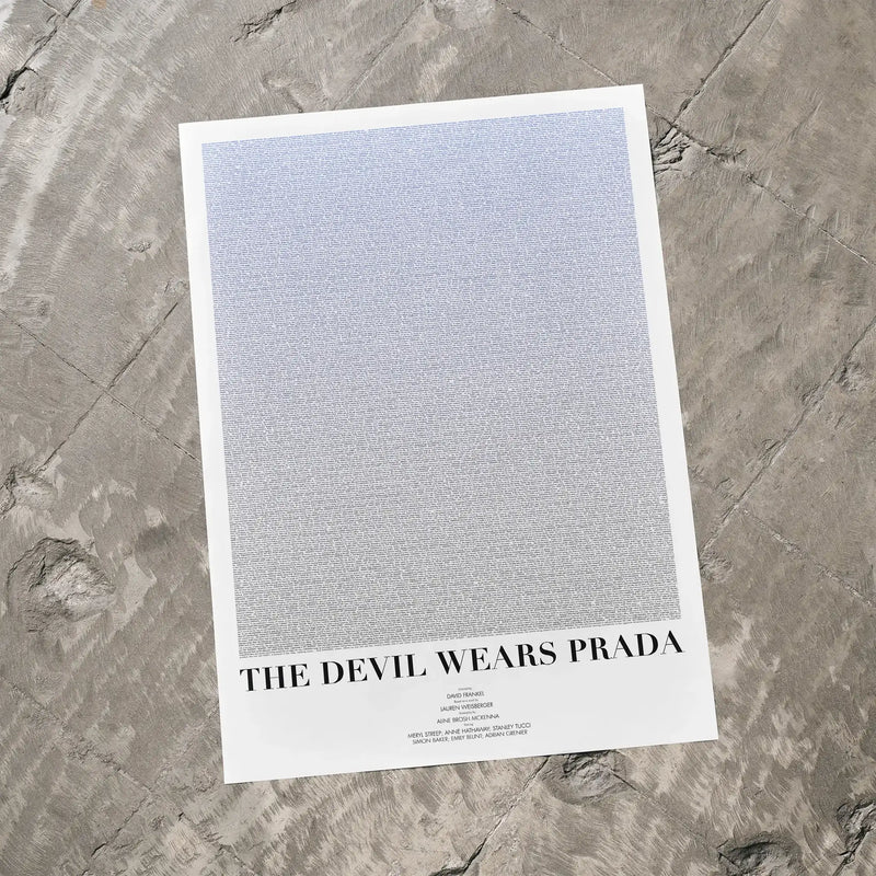 A The Devil Wears Prada movie script poster laid flat on a textured floor surface.