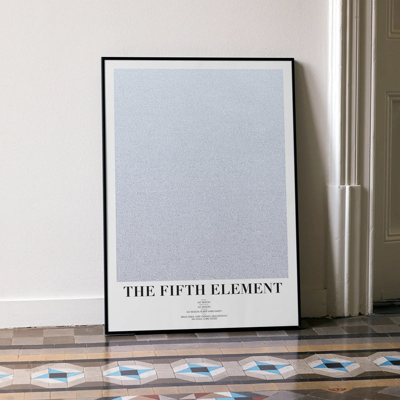 A framed The Fifth Element movie script poster leaning against a wall in a minimalist interior.