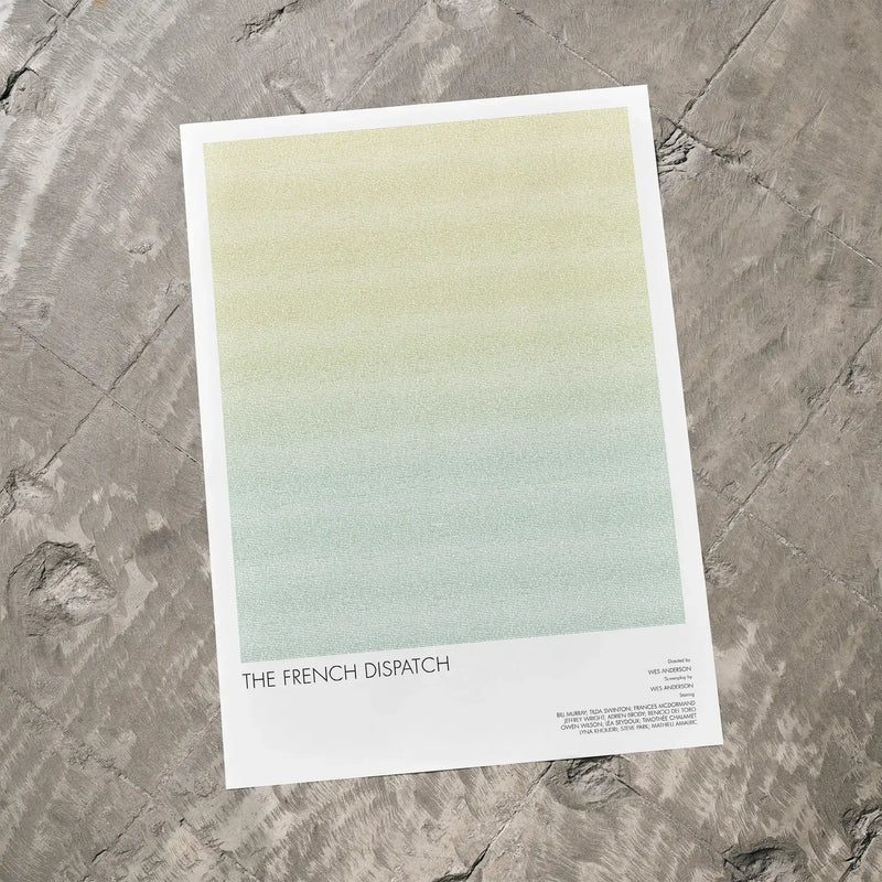 A The French Dispatch movie script poster laid flat on a textured floor surface.