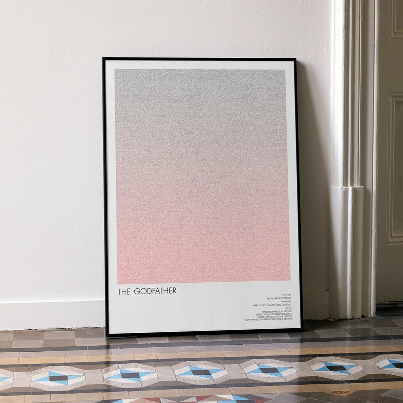 A framed The Godfather movie script poster leaning against a wall in a minimalist interior.