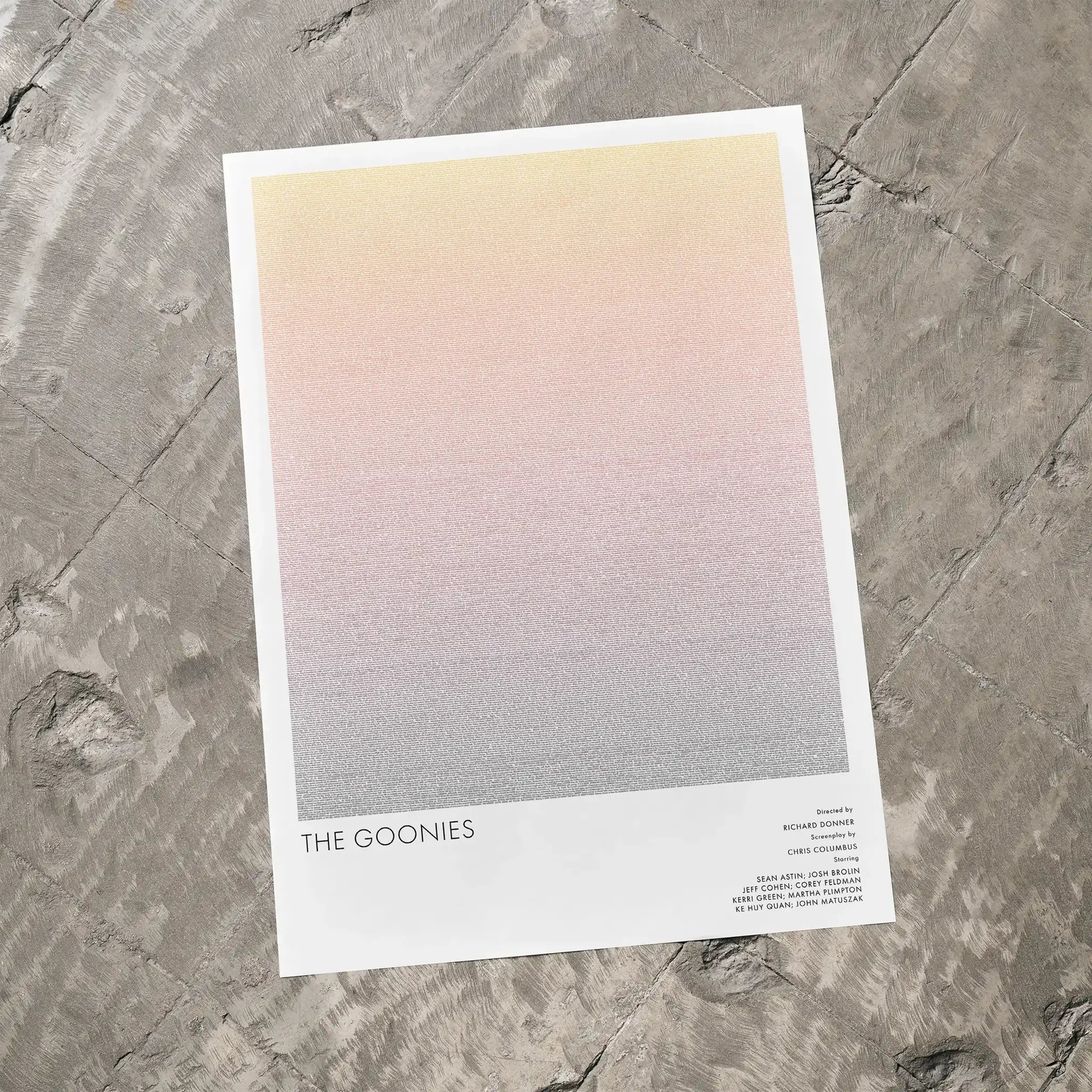 A The Goonies movie script poster laid flat on a textured floor surface.