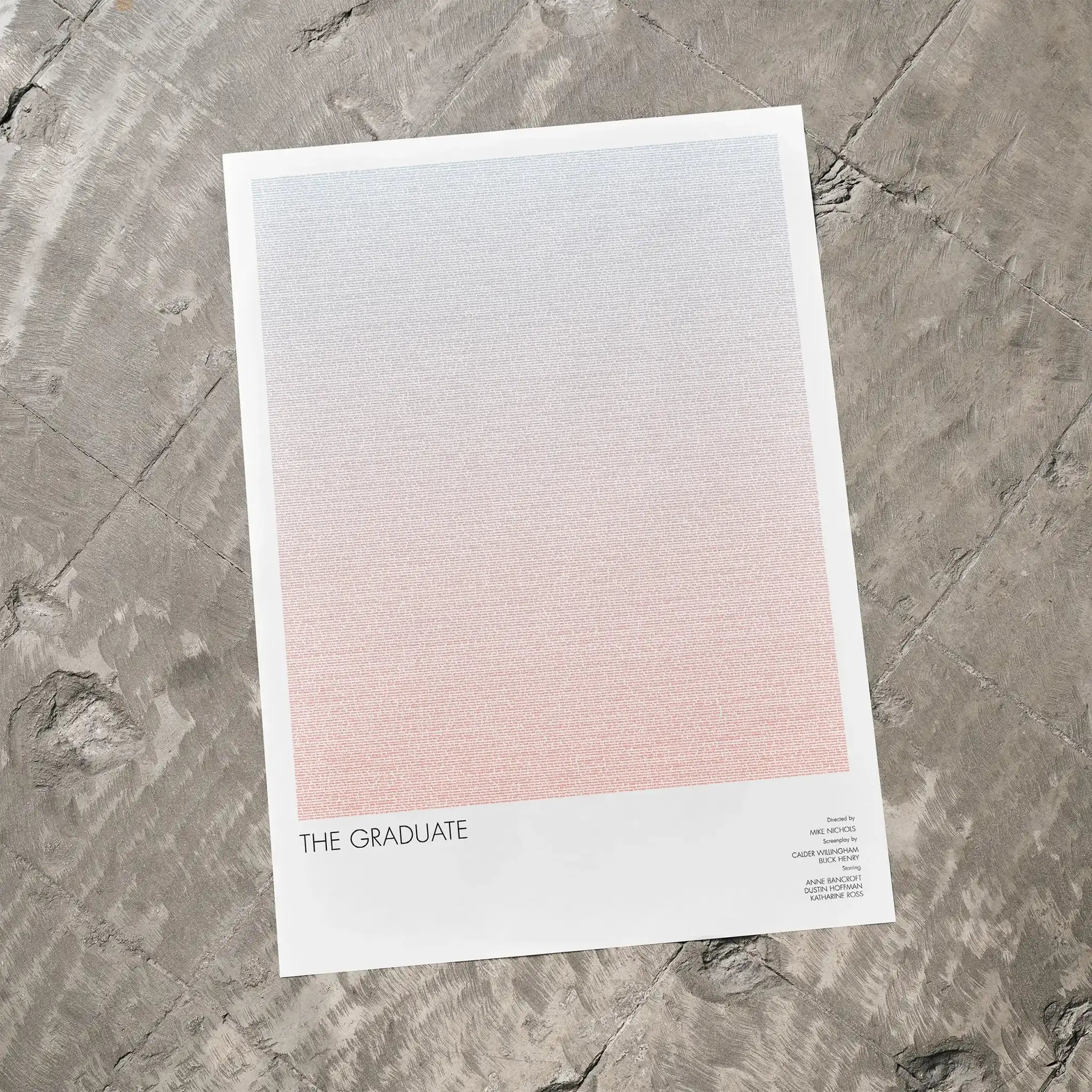 A The Graduate movie script poster laid flat on a textured floor surface.