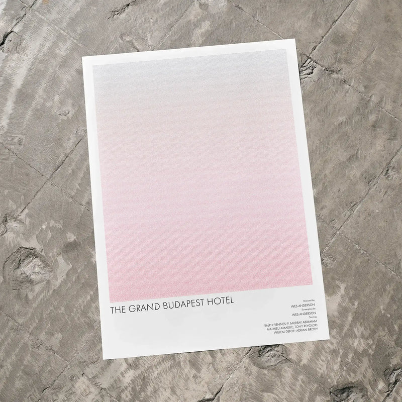 A The Grand Budapest Hotel movie script poster laid flat on a textured floor surface.