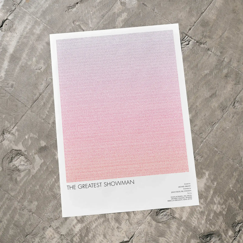 A The Greatest Showman movie script poster laid flat on a textured floor surface.