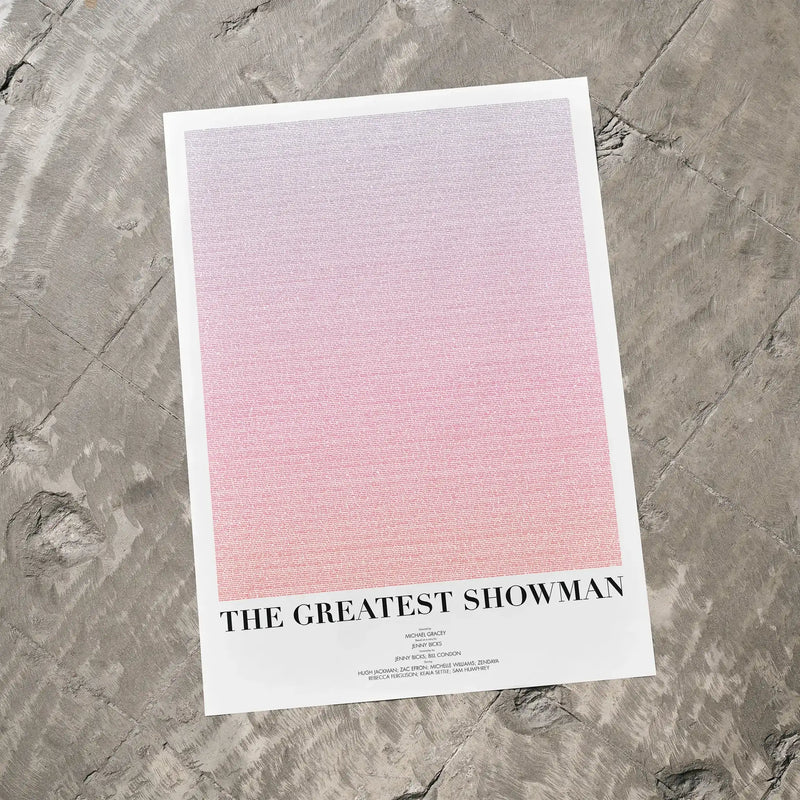 A The Greatest Showman movie script poster laid flat on a textured floor surface.