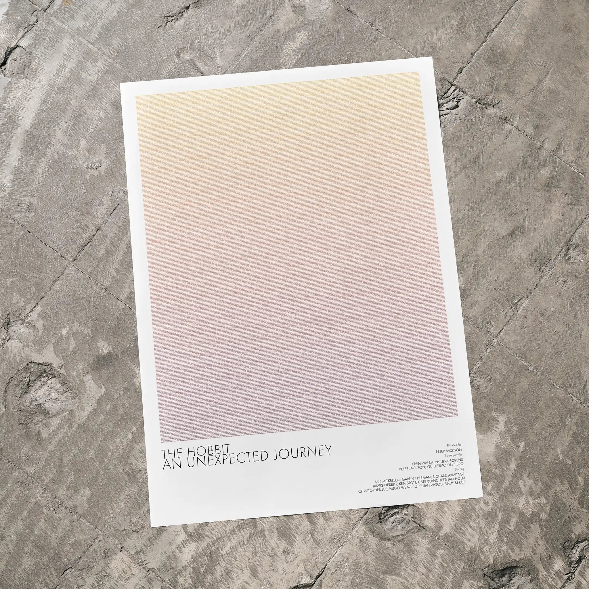 A The Hobbit: An Unexpected Journey movie script poster laid flat on a textured floor surface.