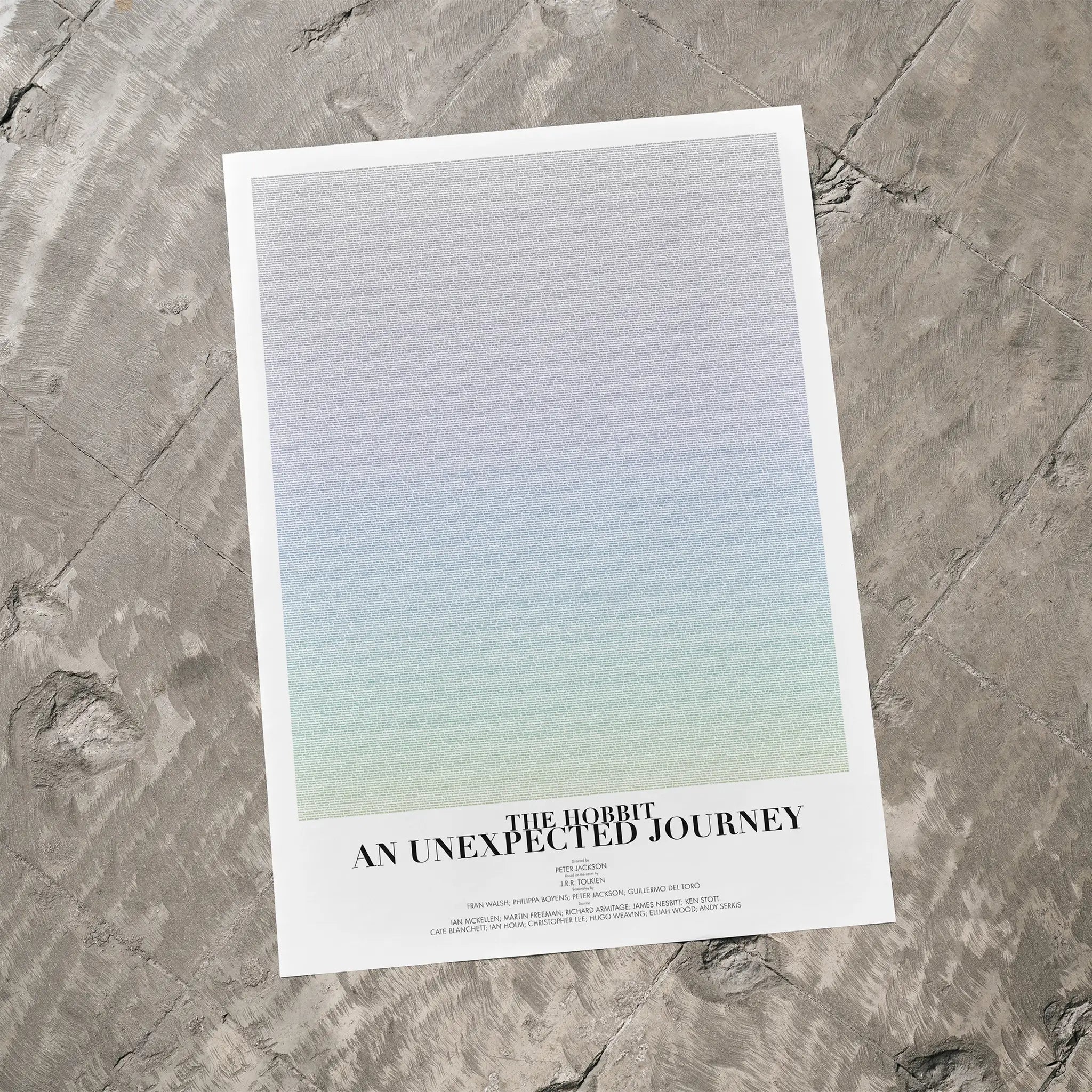 A The Hobbit: An Unexpected Journey movie script poster laid flat on a textured floor surface.