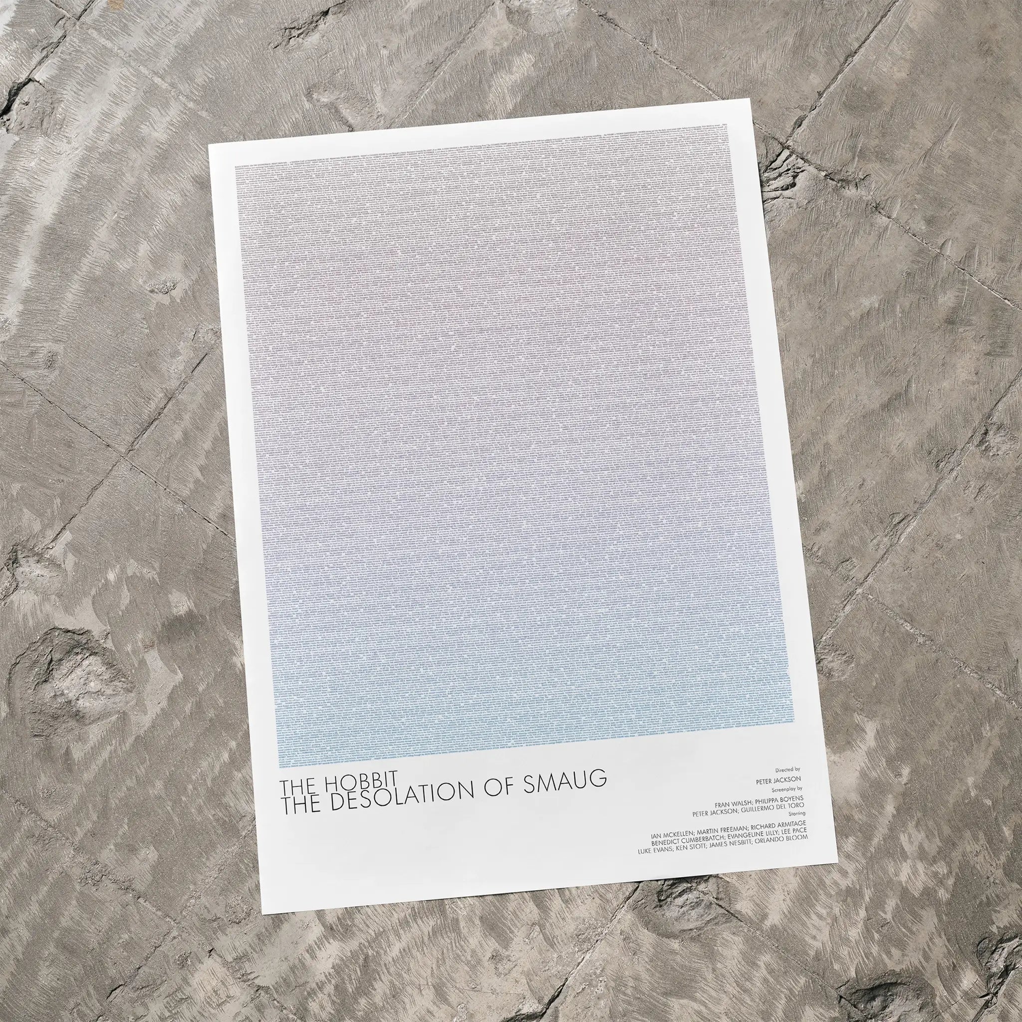 A The Hobbit: The Desolation of Smaug movie script poster laid flat on a textured floor surface.