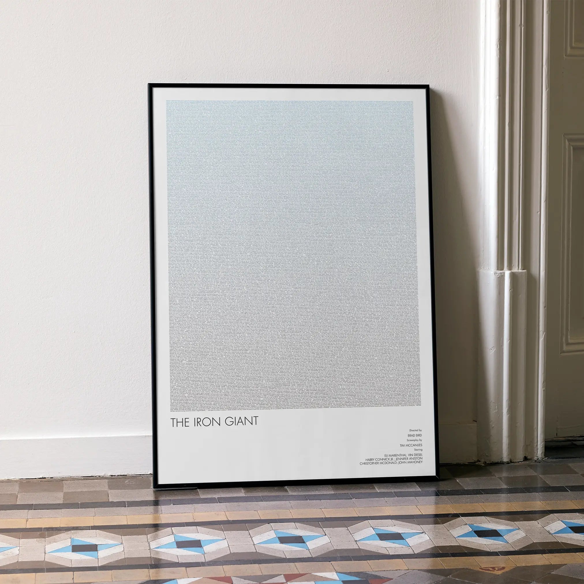A framed The Iron Giant movie script poster leaning against a wall in a minimalist interior.
