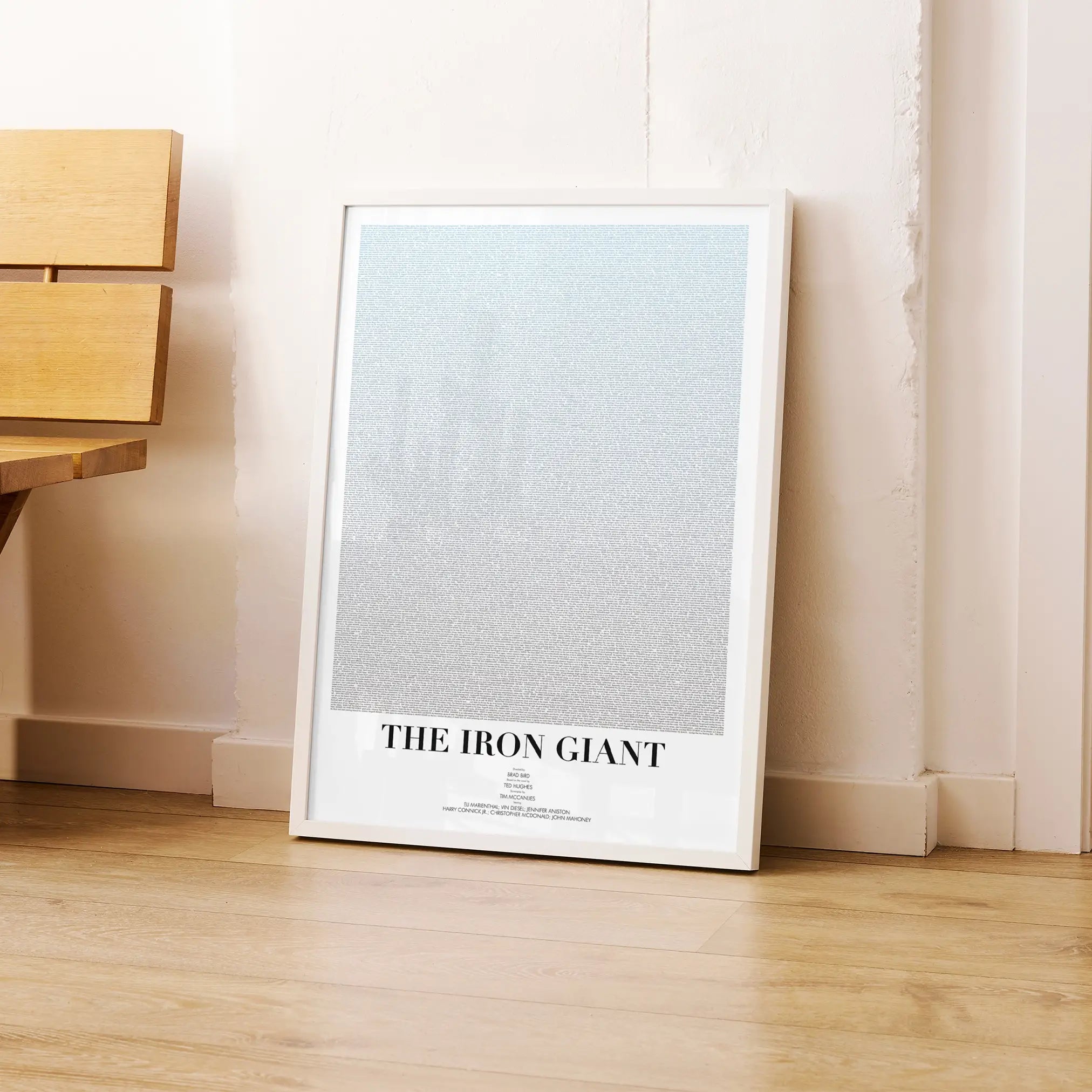 A framed The Iron Giant movie script poster leaning against a wall in a modern interior.