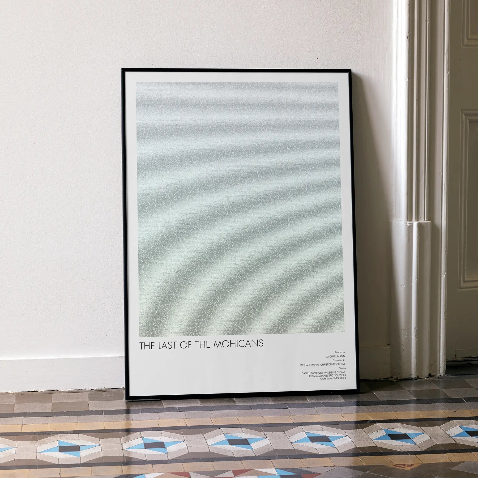 A framed The Last of the Mohicans movie script poster leaning against a wall in a minimalist interior.