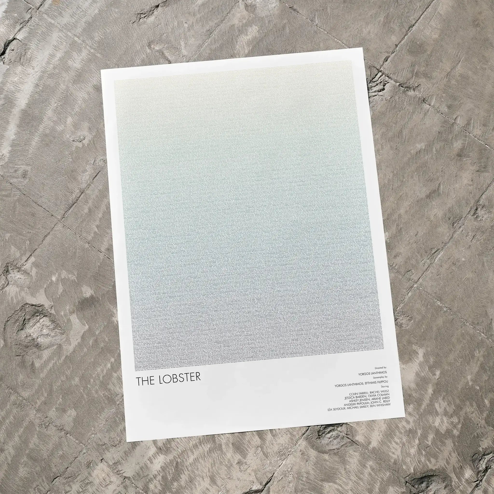 A The Lobster movie script poster laid flat on a textured floor surface.