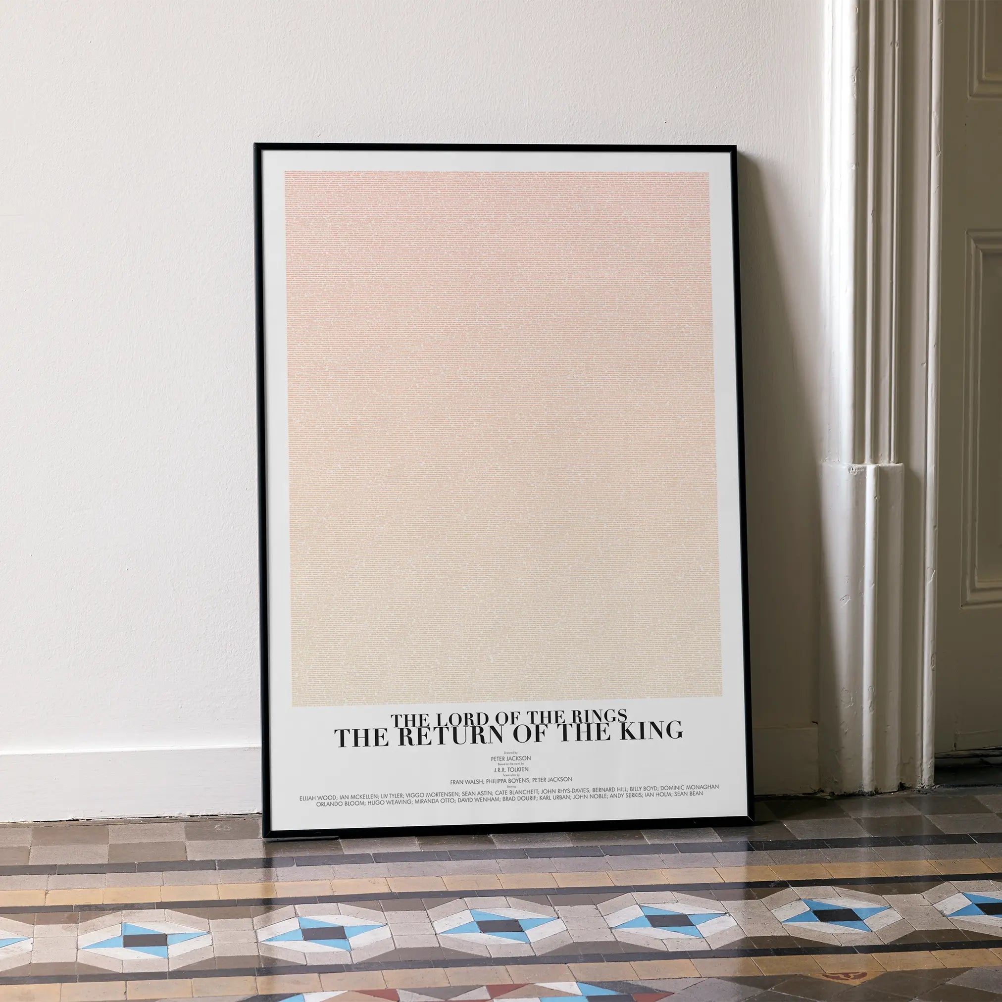 A framed The Lord of the Rings: The Return of the King movie script poster leaning against a wall in a minimalist interior.